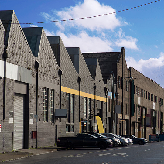 A street view of two styles of brick industrial buildings side-by-side.